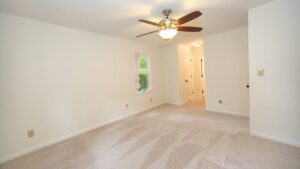 room with white walls and brown ceiling fan after drywall