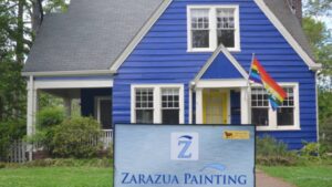 blue home with exterior painting and LGBTQ flag