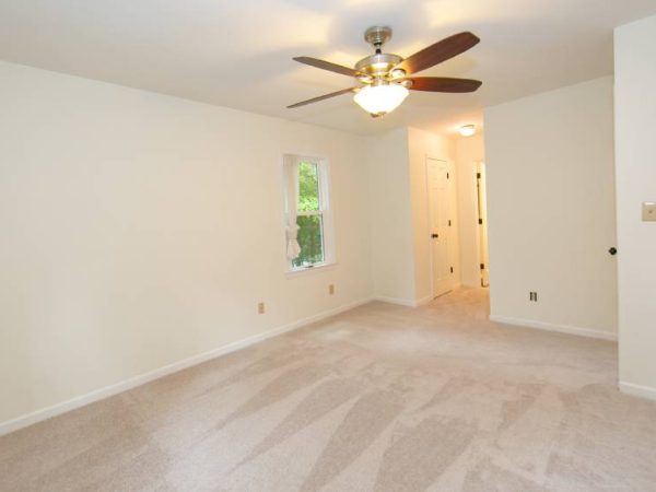 room with white walls and brown ceiling fan after drywall